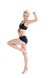 Sporty woman balancing on one leg while stretching out hand