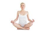Toned young woman sitting in lotus pose with eyes closed