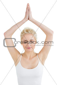 Toned woman with joined hands and eyes closed