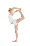 Sporty woman stretching body while balancing on one leg