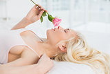 Side view of a pretty woman in bed with rose