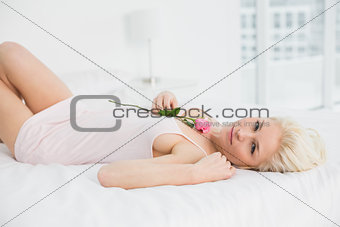 Portrait of a pretty woman resting in bed with rose