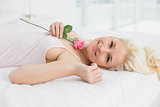 Portrait of a pretty woman resting in bed with a rose