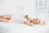 Portrait of a pretty woman resting in bed with a rose