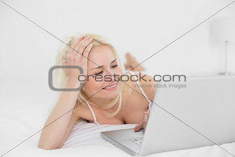 Casual relaxed blond using laptop in bed