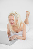 Casual relaxed young blond using laptop in bed