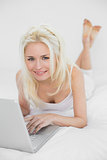 Portrait of a casual relaxed blond with laptop in bed