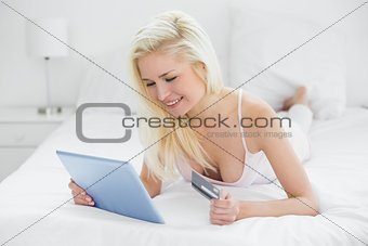 Casual young blond doing online shopping in bed