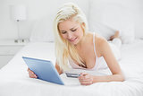 Casual young blond doing online shopping in bed