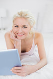 Smiling casual young blond with tablet PC in bed