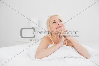 Young woman with joined hands lying in bed