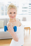 Smiling woman with dumbbell at fitness studio