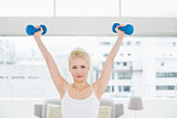 Serious woman lifting dumbbells at fitness studio