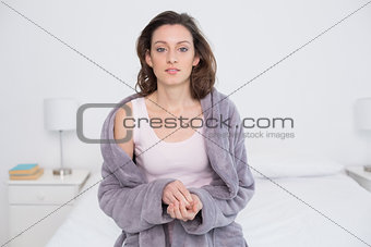 Beautiful young woman in bathrobe sitting in bed