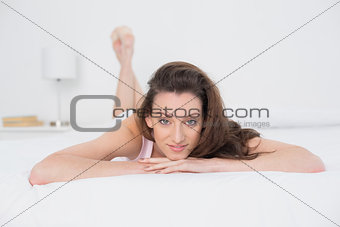 Full length portrait of a smiling woman resting in bed
