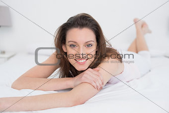 Full length portrait of smiling woman resting in bed