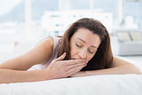 Woman yawning with eyes closed in bed