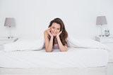 Portrait of a pretty smiling woman resting in bed