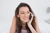 Close up of smiling woman using mobile phone in bed