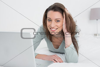 Relaxed casual smiling woman using laptop in bed