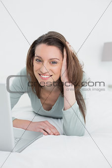 Relaxed casual smiling woman using laptop in bed