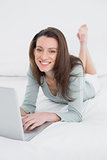 Relaxed casual smiling young woman using laptop in bed