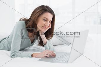 Relaxed casual woman using laptop in bed