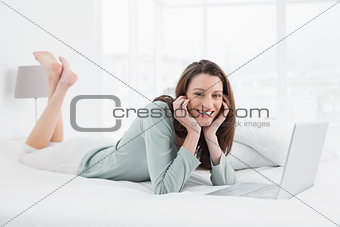 Relaxed casual smiling woman with laptop in bed