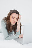 Casual sad young woman using laptop in bed