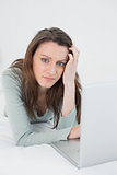 Relaxed casual sad young woman using laptop in bed