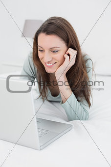 Happy relaxed casual woman using laptop in bed
