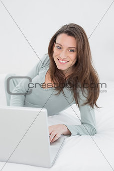 Happy relaxed casual woman using laptop in bed