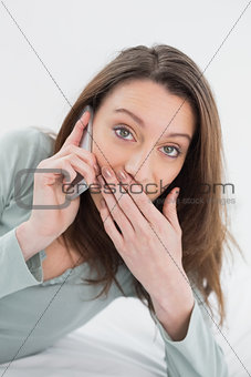 Shocked casual young woman using cellphone in bed