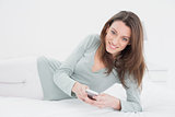 Smiling young woman with mobile phone in bed