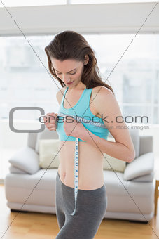 Toned woman measuring chest in fitness studio