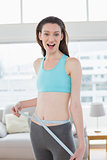 Shocked toned woman measuring waist in fitness studio