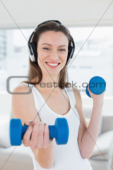 Fit woman exercising with dumbbells in fitness studio