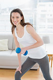 Fit woman exercising with dumbbell in fitness studio