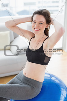Fit woman sitting on exercise ball in fitness studio