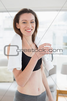 Fit woman holding water bottle in fitness studio