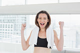 Cheerful woman clenching fists in fitness studio
