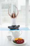 Blurred woman in meditation posture with healthy food in foreground