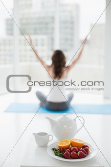Woman sitting in meditation posture with healthy food in foreground