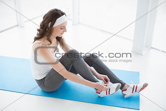 Toned woman wearing shoes on exercise mat at fitness studio