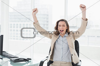 Elegant businesswoman cheering with hands raised in office