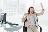 Businesswoman cheering with hands raised in office