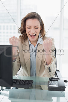 Businesswoman cheering with clenched fists in office