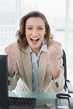 Businesswoman cheering with clenched fists in office