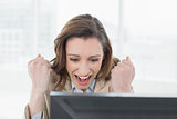 Businesswoman cheering with clenched fists at office desk