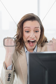 Elegant businesswoman cheering at office desk